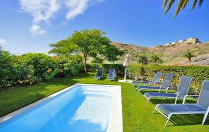 a group of chairs sitting next to a swimming pool at Salobre Las Tabaibas 1 in Maspalomas