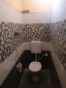 ein Bad mit einem WC in einer gefliesten Wand in der Unterkunft Selvalakshmi Restaurant and Lodge in Tiruvannāmalai