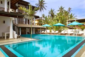 a pool at a resort with chairs and umbrellas at Beach Inns Holiday Resort in Matara