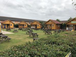 a group of picnic tables in a park with wooden buildings at Bacchus Hotel Log Cabins in Sutton on Sea