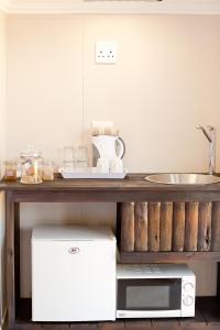 a kitchen with a counter with a sink and a microwave at Cavallo Guesthouse in Windhoek +18 photos