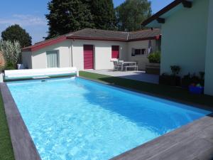 a large blue swimming pool in front of a house at La clé de vos Rêves in Orthevielle