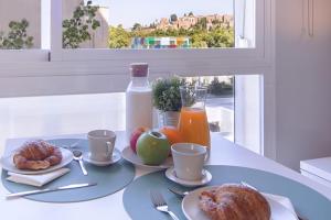 einen Tisch mit einem Frühstück mit Croissants und Orangensaft in der Unterkunft Malagueta Cool Beach Apartment in Málaga