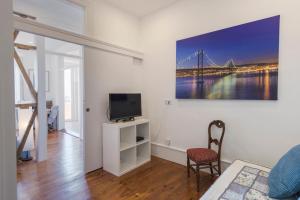 ein weißes Wohnzimmer mit einem TV und einem Stuhl in der Unterkunft LovelyStay - Comfortable apartment with river views in Lissabon