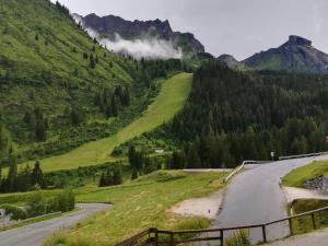 uma estrada sinuosa numa montanha com árvores e nuvens em Appartamento Gliera em Arabba