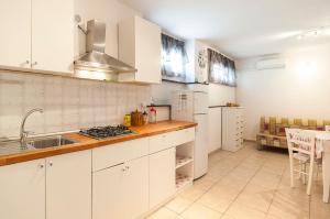 uma cozinha com armários brancos, um lavatório e um fogão em Appartamento Chicca em Sperlonga