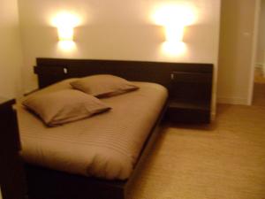 a bed with two pillows and two lights on the wall at le pirate in Granville