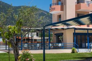 a building with a blue and white umbrella and a tree at Akroyiali Resort in Vasiliki