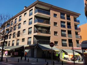 a tall brick building on a city street with people in front at Apartaments Ponent in Lloret de Mar