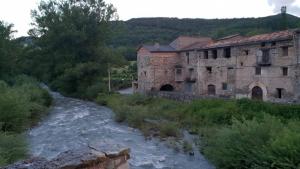 a river in front of an old stone building at Casa Antonia in Vilaller