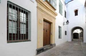 コルドバにあるEl 5 de la Hogueraの白い建物と茶色の扉のある路地