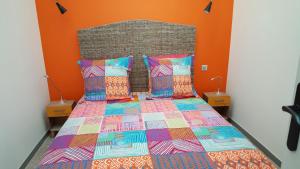a bed with a colorful comforter and two pillows at Villa Tramontane in Le Grau-du-Roi