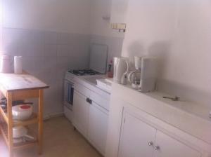 a small white kitchen with a stove and a table at le flibustier in Granville