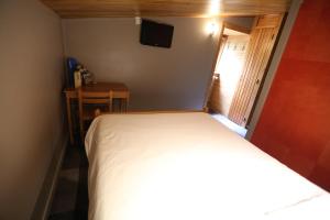 Schlafzimmer mit einem Bett, einem Tisch und einem TV in der Unterkunft Gîte-Hôtel Le P'tit Cham in Le Mont-Dore
