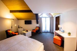 ein Hotelzimmer mit einem Bett, einem Schreibtisch und Stühlen in der Unterkunft Ochsen Lenzburg in Lenzburg