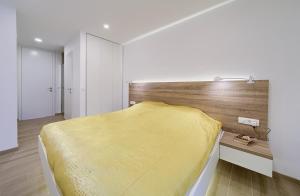 - une chambre avec un lit jaune et une tête de lit en bois dans l'établissement Villa Celeia, à Krk