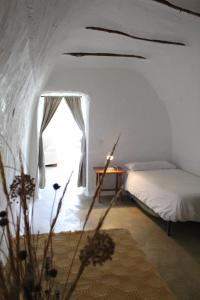 a bedroom with a bed and a table and a window at Cueva El Ermitano in Baza