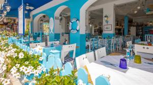 un ristorante con tavoli e sedie blu e fiori di Hotel Paolina a Lido di Jesolo