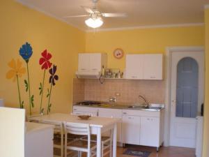 a kitchen with white cabinets and a table with a vase at Casa Gialla in Imperia