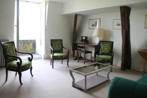 a living room with green chairs and a table at Gîte Le Haut Perché 4 pers. in Saint-Gervais-la-Forêt