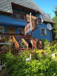 a blue house with wooden decks and flowers at Szőlőskert Apartman in Cserszegtomaj