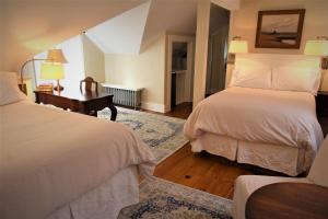a bedroom with two beds and a desk with two lamps at The Oak Bluffs Inn in Oak Bluffs