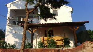 ein weißes Haus mit einem Balkon und einem Baum in der Unterkunft Tajči in Ugljan