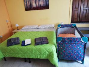 オメーニャにあるBed and Breakfast Porta Romanaのベッドルーム1室(緑の毛布とスーツケース付きのベッド1台付)