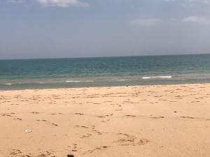 una spiaggia con impronte di piedi nella sabbia e nell'oceano di Appartement Kabila Marina a M'diq
