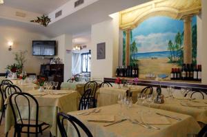 a restaurant with tables and chairs and a painting on the wall at Hotel Rivamare in Massignano