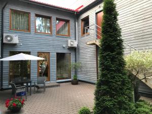a house with a patio with a table and an umbrella at Vila Saulė in Palanga
