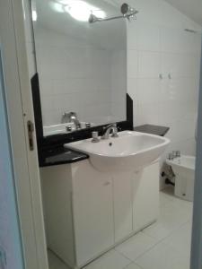 een witte badkamer met een wastafel en een spiegel bij La mansarda dello scultore in Niscemi
