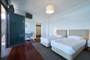 a bedroom with two beds and a sliding glass door at Marina Rooms in Calheta