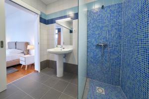 a bathroom with a sink and a shower with blue tiles at Marina Rooms in Calheta