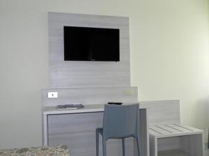 a desk with a chair and a television on a wall at Albergo Sant'Anna in Solbiate Olona
