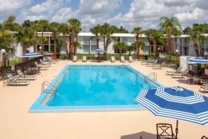 a swimming pool with umbrellas and chairs and a hotel at Stayable Kissimmee East in Kissimmee