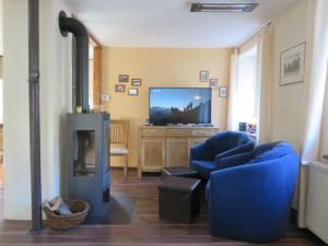 a living room with a blue chair and a television at Petit Papillon in Soultzeren