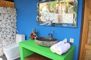 a bathroom with a sink and a toilet and a mirror at The Calmtree Bungalows in Canggu