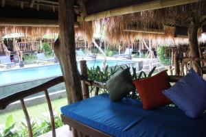 a person sitting on a bed in front of a beach at The Calmtree Bungalows in Canggu