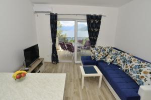 a living room with a blue couch and a tv at Apartmani M&E in Tivat
