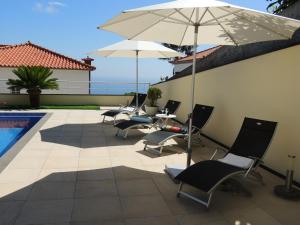eine Terrasse mit Stühlen und Sonnenschirmen neben einem Pool in der Unterkunft Studio Flat with Pool in Funchal