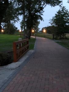 a brick walkway with a fence and trees at night at Hayungshaus Esens in Esens