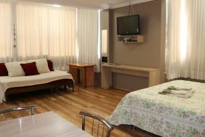 a room with two beds and a couch and a tv at Solar do Centro in Gramado