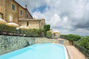 a swimming pool in front of a building with umbrellas at Hotel Dei Capitani in Montalcino