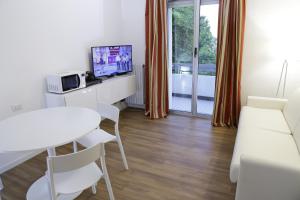 a room with a desk with a television and a table at Family Suite Appartments Orchidea Blu in Rimini