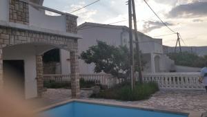 a villa with a swimming pool in front of a house at Apartmani Vuksanović in Pag