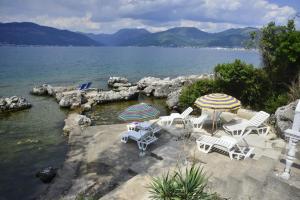 a group of chairs and umbrellas next to the water at Apartmani M&E in Tivat