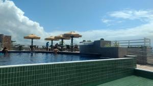 Pipa's Bay - Flats para temporada في بيبا: مسبح مع مظلات فوق المبنى