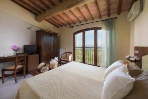 a bedroom with a bed and a desk and a window at Hotel Dei Capitani in Montalcino