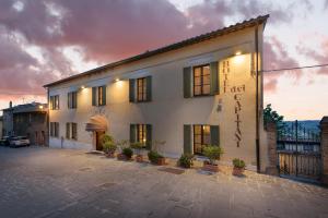 een groot wit gebouw met planten op een binnenplaats bij Hotel Dei Capitani in Montalcino